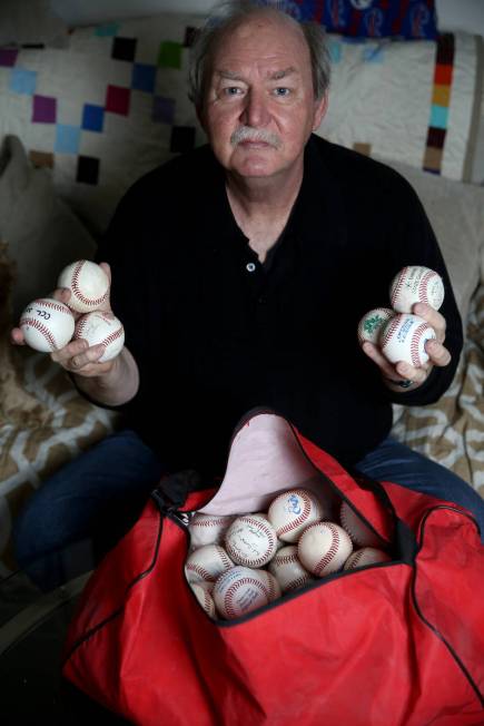 High school umpire Jim Bullock shows collectable baseballs from every league he worked at his L ...