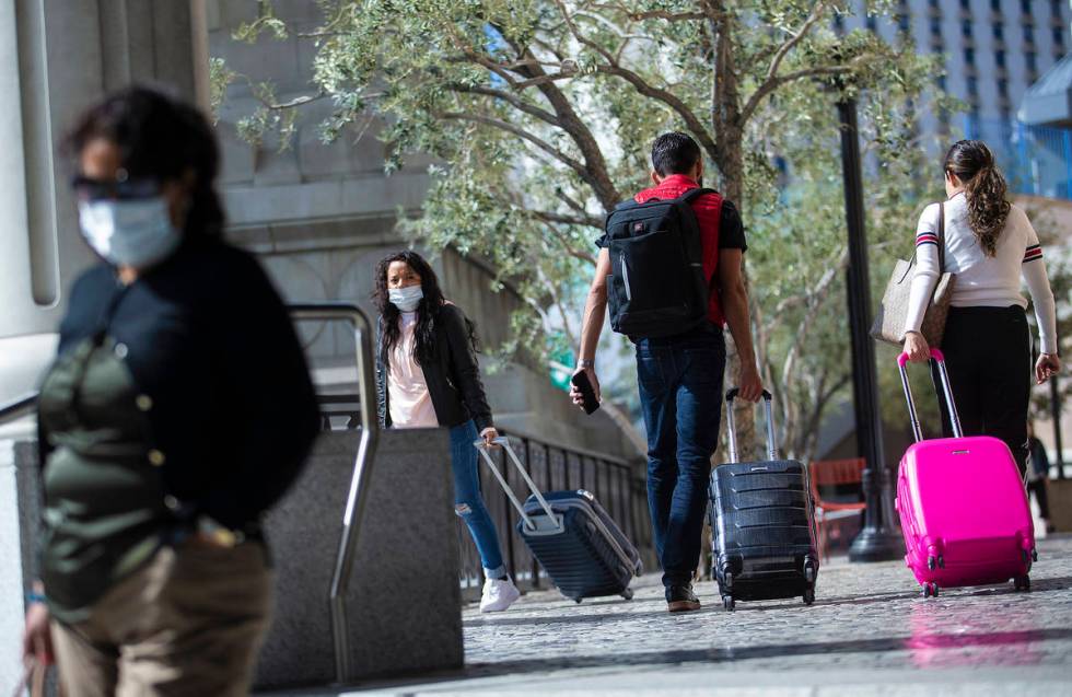 Tourists wearing medical masks make their way along the Strip on Tuesday, March 17, 2020, in La ...