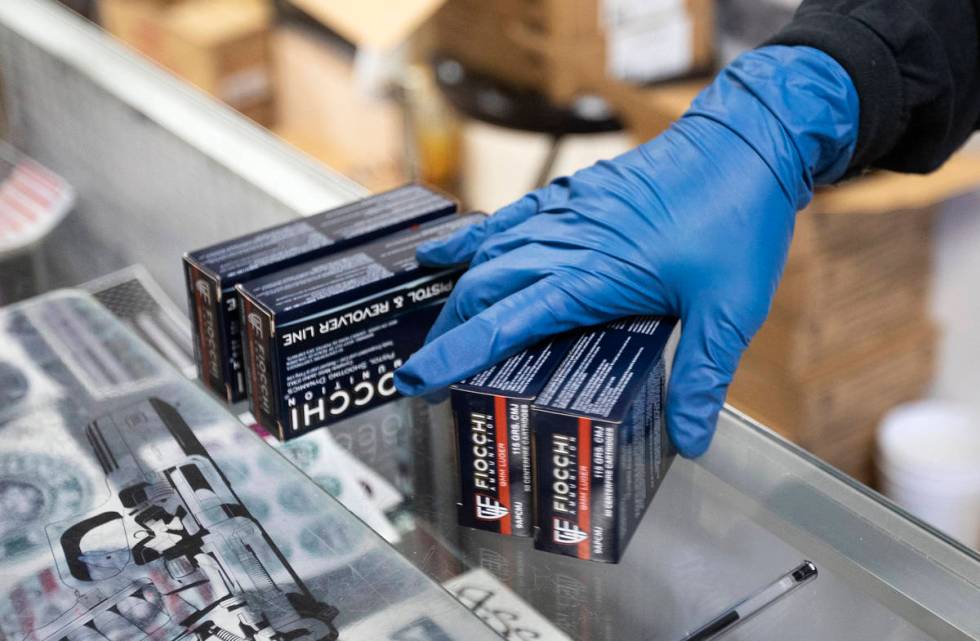 An employee at 2nd Amendment Gun Shop uses gloves while bagging ammunition for a customer on Tu ...