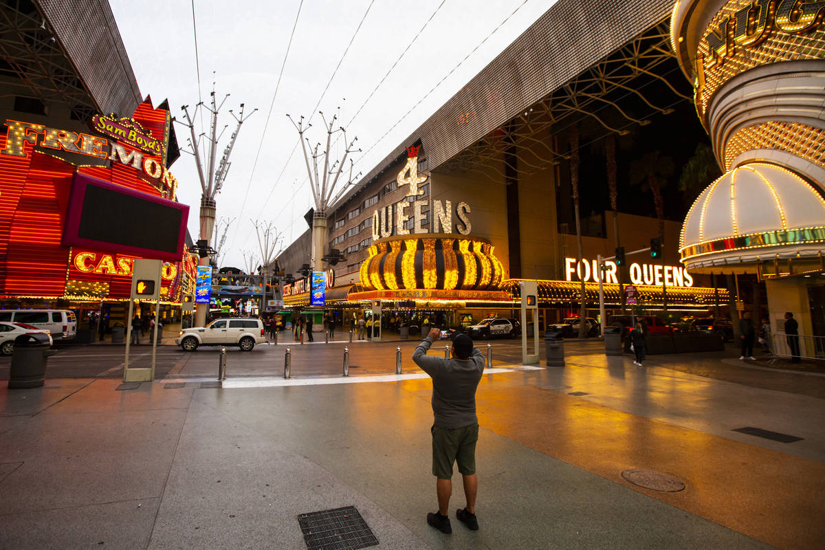 A man takes a photo of the Fremont Street Experience following Gov. Steve Sisolak's statewide o ...