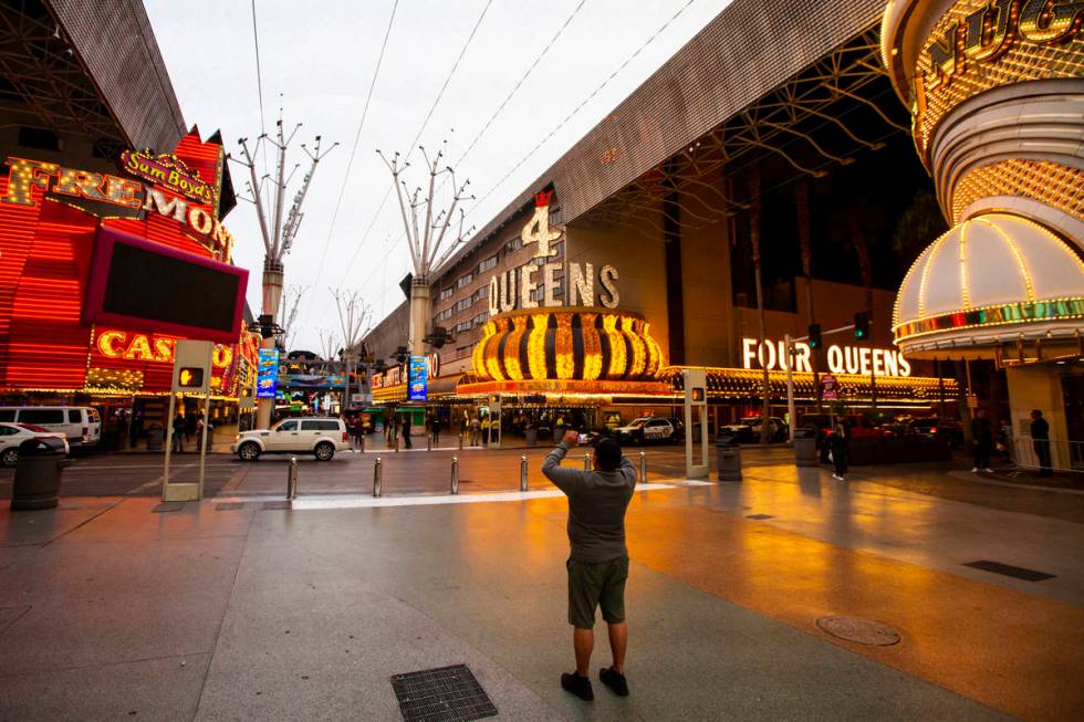 A man takes a photo of the Fremont Street Experience following Gov. Steve Sisolak's statewide o ...
