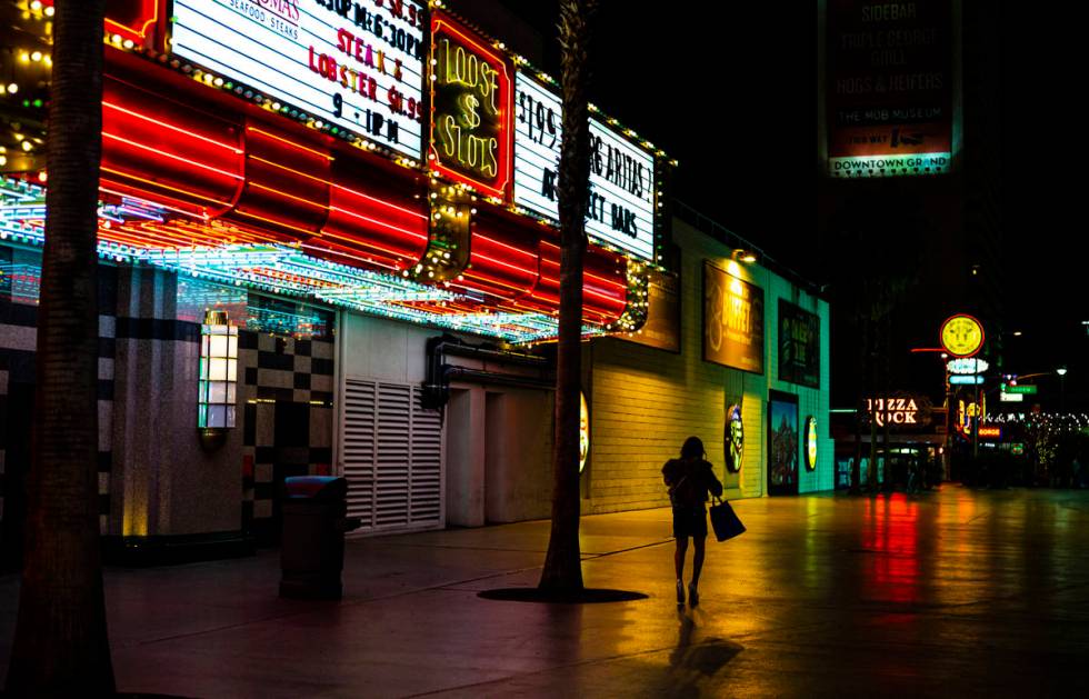 A woman walks away from the Fremont Street Experience following Gov. Steve Sisolak's statewide ...