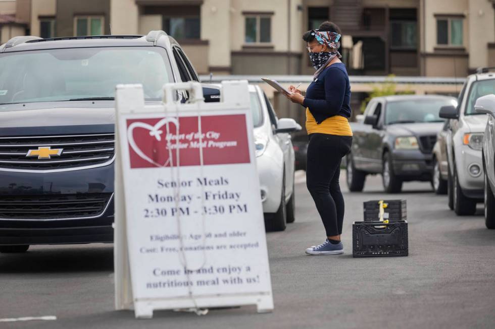 Community health worker for Lutheran Social Services of Nevada A.J. Tullos, greet a vehicle in ...
