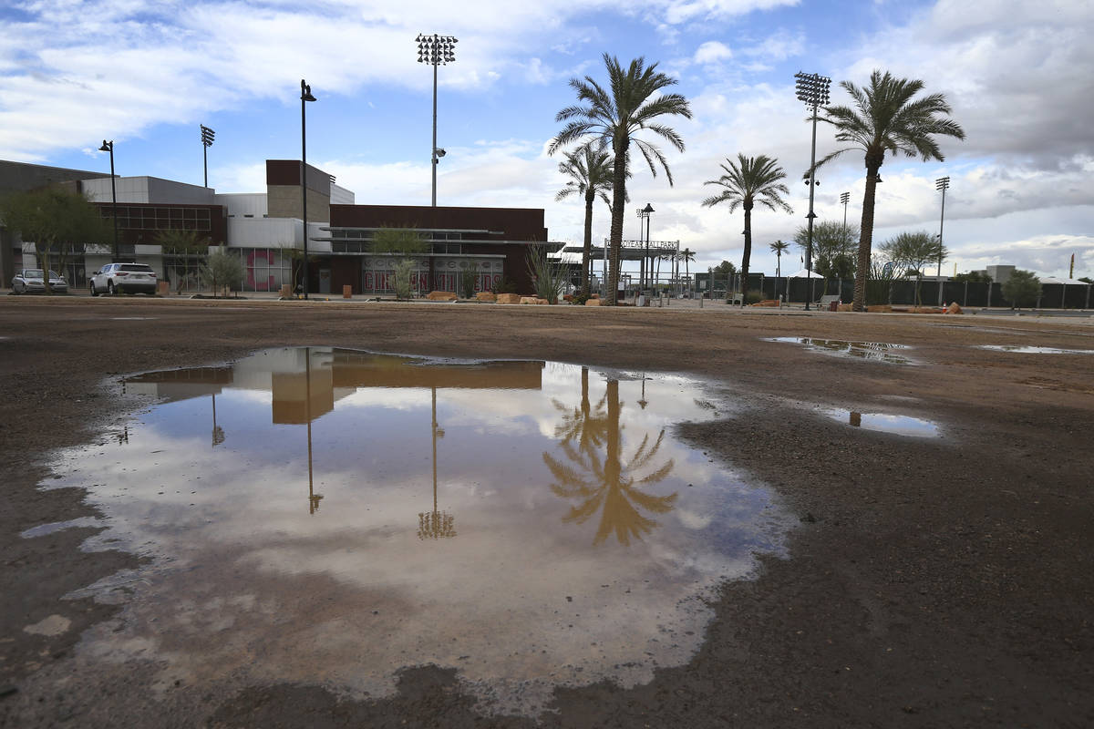 A puddle in an empty parking lot reflects a closed Goodyear Ballpark, home of the Cleveland Ind ...