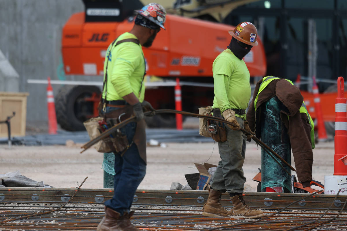 Workers carry rebar steel at the Raiders Allegiant Stadium construction site in Las Vegas, Wedn ...