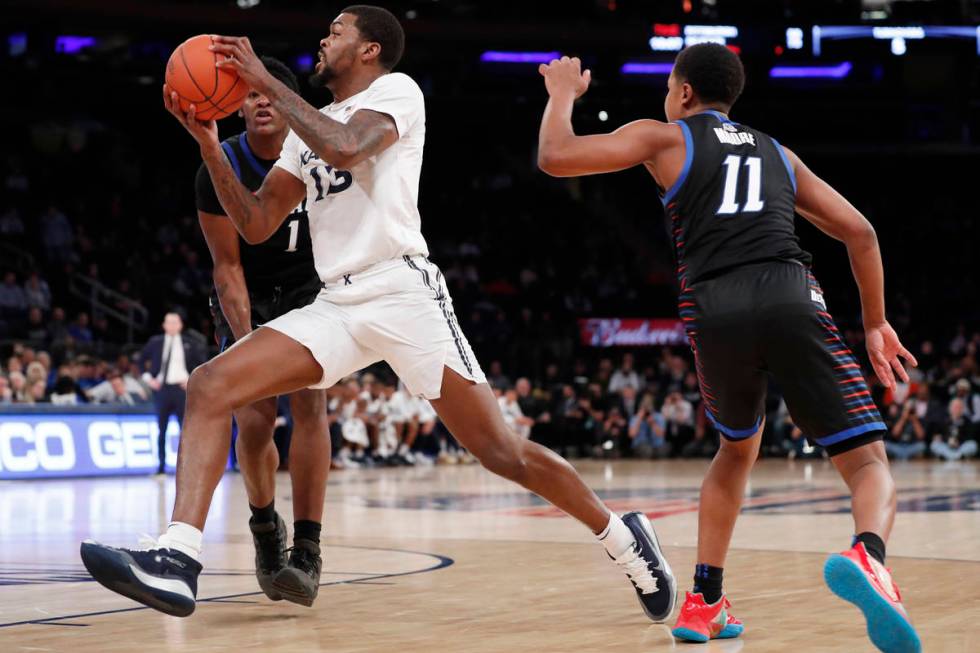 Xavier forward Naji Marshall (13) drives between DePaul guard Charlie Moore (11) and forward Ro ...