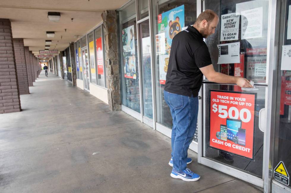Eathan Upchurch wipes the door handle of the GameStop store at 2119 East Lake Mead Boulevard, w ...