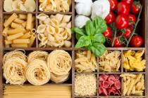 Assorted pastas in wooden box with cooking ingredients