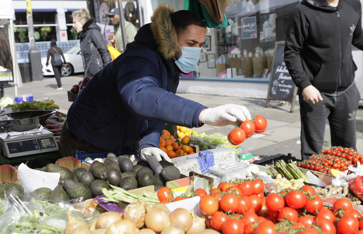 A fruit and vegetable stall holder wears a mask and gloves amid the COVID-19 virus outbreak in ...