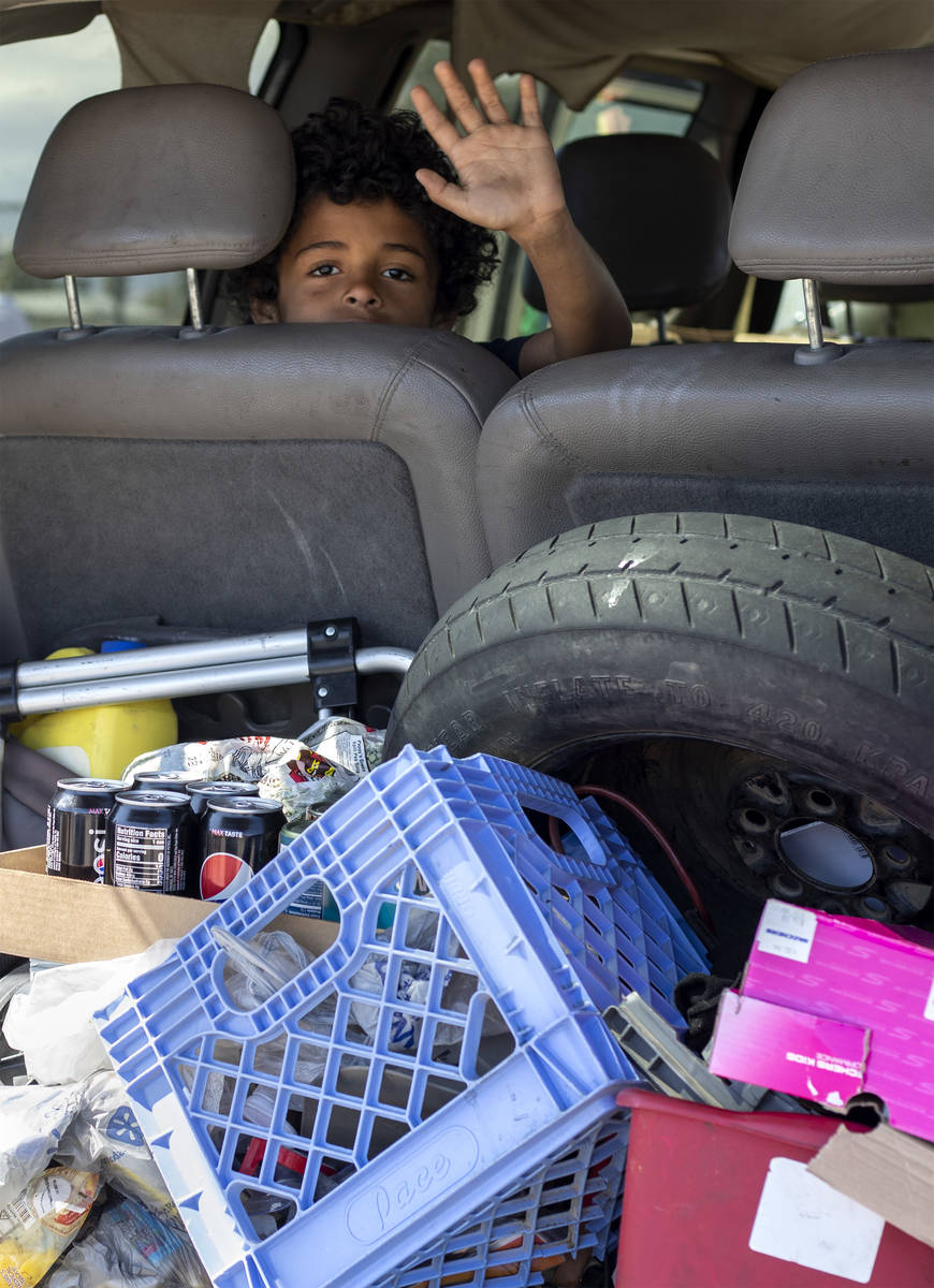 Eight-year-old Masen Flowers waves out of his mother's van as they drive through a food bank ho ...