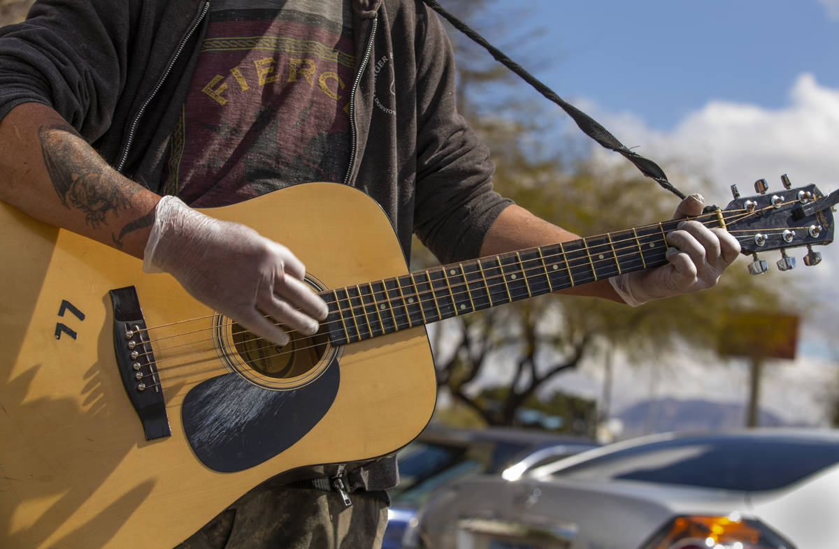 Street musician Kurtis "ToeJam" Nelson plays with plastic gloves on for safety when r ...
