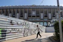A woman wearing a protective mask walks past Real Madrid's Santiago Bernabeu stadium in Madrid, ...