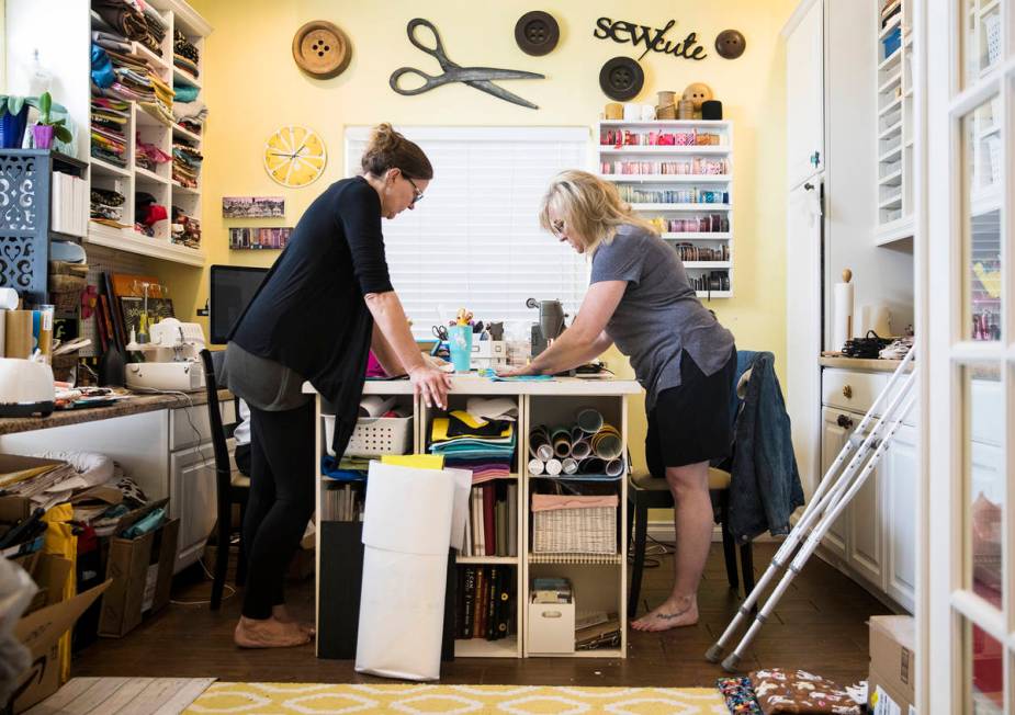 Anissa Gustafson, right, shows her friend Terri Yannone, left, how to cut fabric for masks at h ...