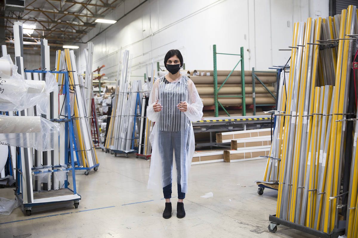 Employee Jordan Mevius wearing a gown and mask at Polar Shades in Las Vegas, Monday, March 23, ...