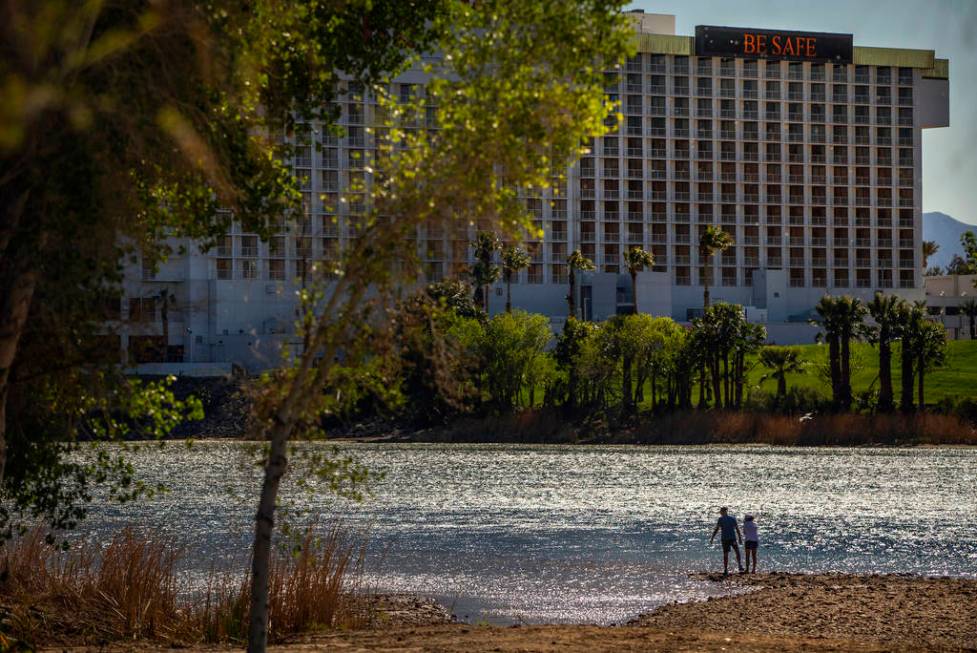 A couple stands beside the Colorado River running beside Laughlin where the town is nearly shut ...