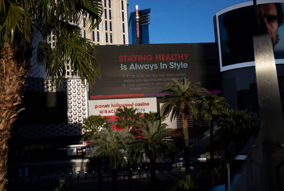 The sun begins to set on a marquee at Planet Hollywood that has a message of health and wellnes ...