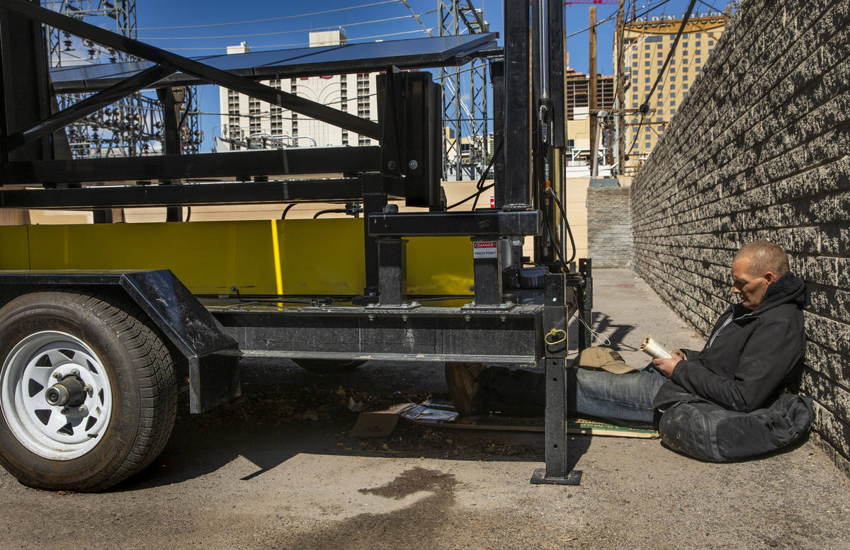 Jason Miller reads a book as he charges up his phone on Monday, March 23, 2020 in Las Vegas, ha ...