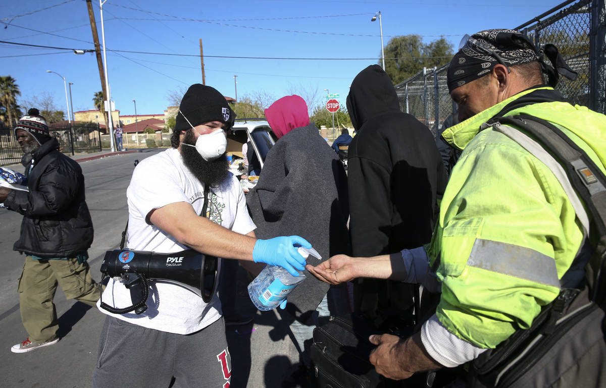 Joey Lankowski of homeless outreach organization Food Not Bombs squirts hand sanitizer for peop ...