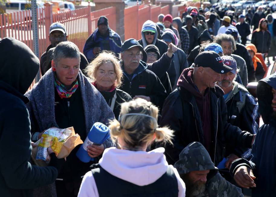 People line up for sack lunches, hygiene kits and blankets from homeless outreach organization ...