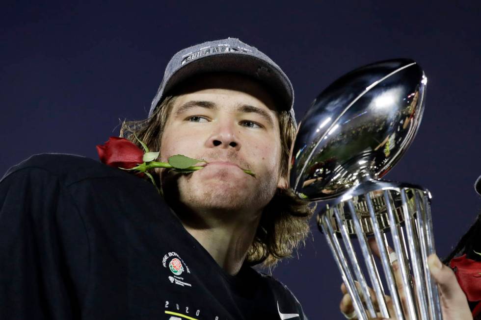 Oregon quarterback Justin Herbert celebrates with the trophy after their win against Wisconsin ...