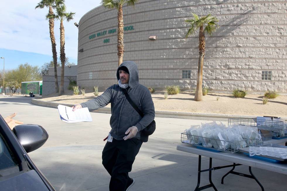 Clark County School District employee Greggy Malimban helps pass out food and homework assignme ...