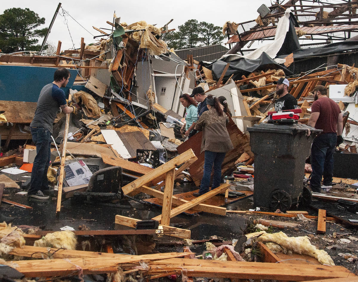 A group of people help clear debris and salvage items from Pawn Depot after a tornado touched d ...