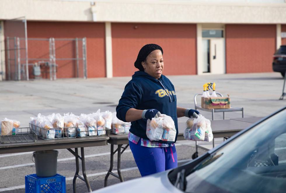 A Clark County School District employee hands out breakfast and lunch packages to families at C ...