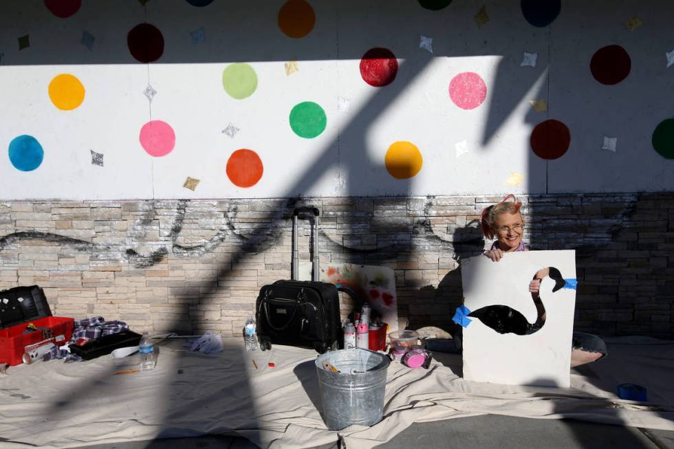 Artist Sheridee Hopper greets a friend while preparing a stencil for her mural on the boarded u ...