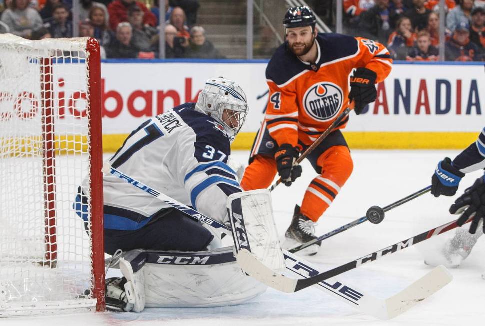 Winnipeg Jets goalie Connor Hellebuyck (37) makes a save as Edmonton Oilers' Zack Kassian (44) ...