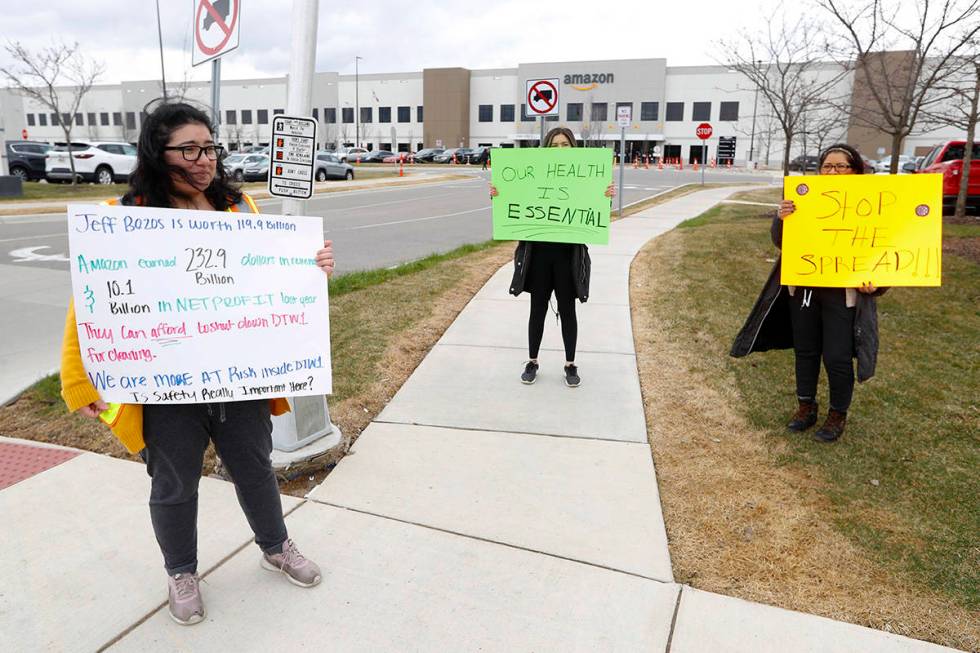 Breana Avelar, left, a processing assistant and family members, hold signs outside the Amazon D ...