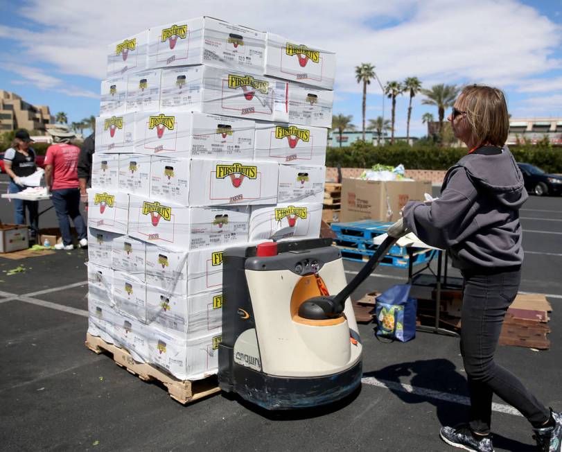 Three Square Food Bank warehouse assistant Kari Guerrero moves boxes of fresh fruit to give out ...