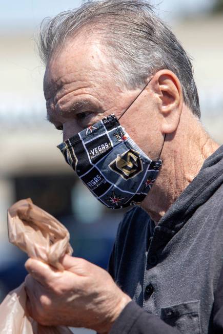 Michael McGowan wears a mask made out of Vegas Golden Knights fabric as he loads his car in the ...