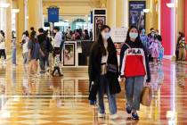 Shoppers wearing masks stroll through the Shoppes at Venetian on April 10, 2020 in Macao. (Insi ...