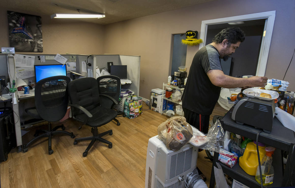 Jeremy Ferreira prepares some dinner for his family within a small office space they are tempor ...