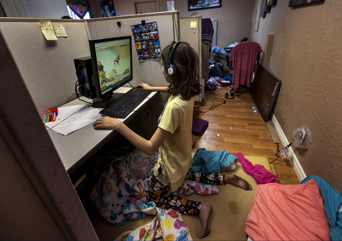 Aubrie Heenan, 17, left, plays Animal Crossing within her makeshift bedroom in a small office s ...