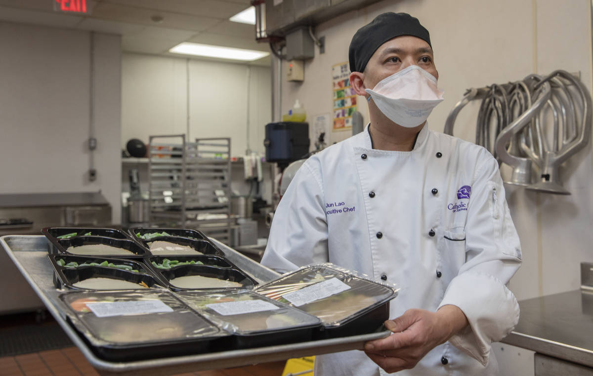 Catholic Charities of Southern Nevada's executive chef Jun Lao carries different dishes to be d ...