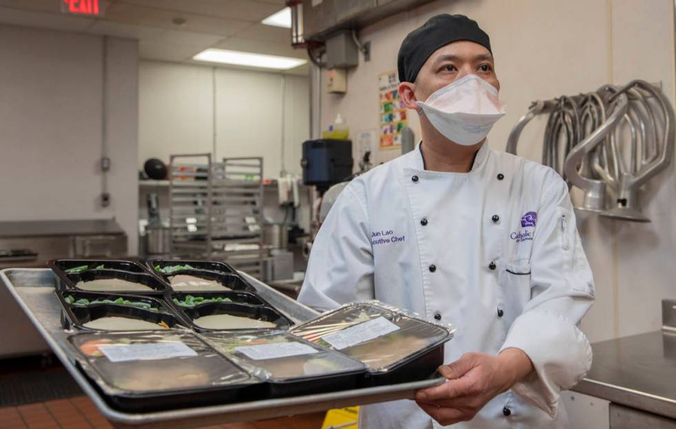 Catholic Charities of Southern Nevada's executive chef Jun Lao carries different dishes to be d ...
