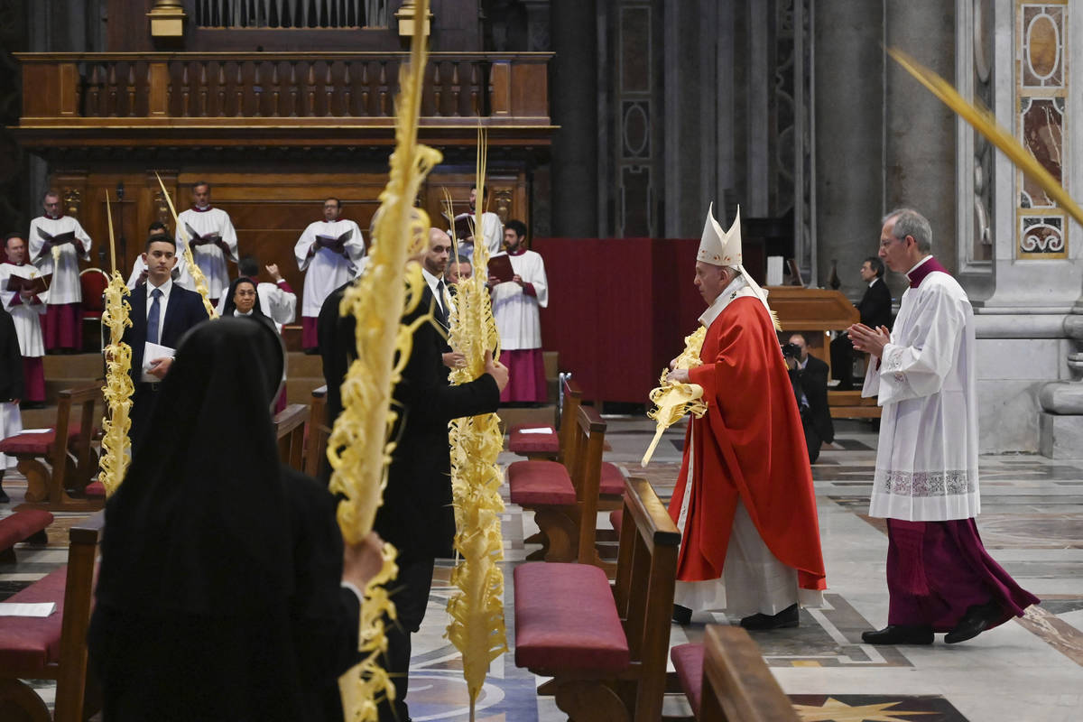 Pope Francis holds a palm branch as he celebrates Palm Sunday Mass behind closed doors in St. P ...