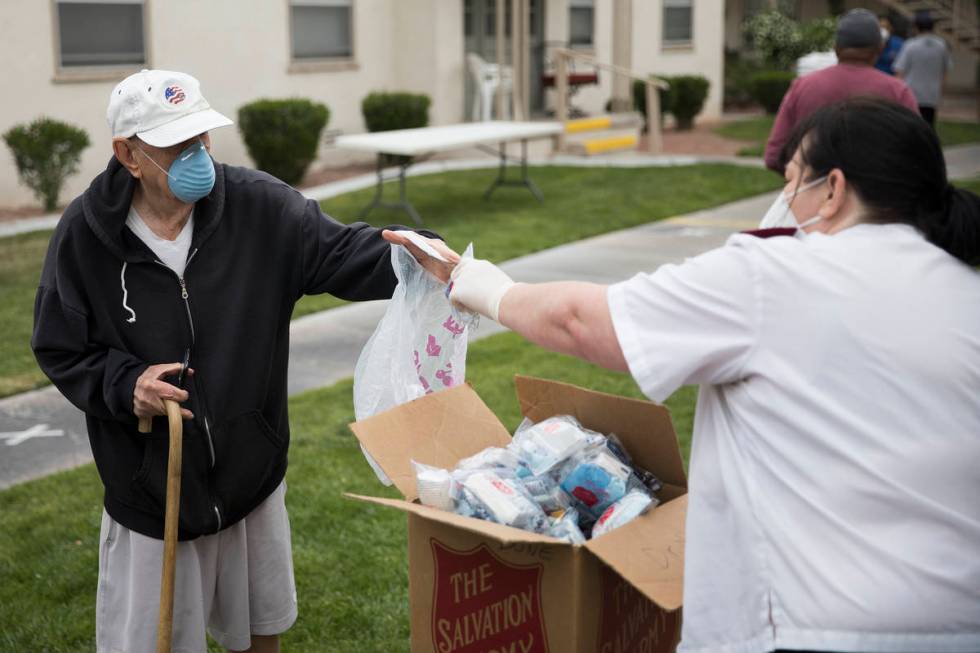 Heather Baze, a lieutenant with the Salvation Army, hands out a coronavirus preparedness kit to ...