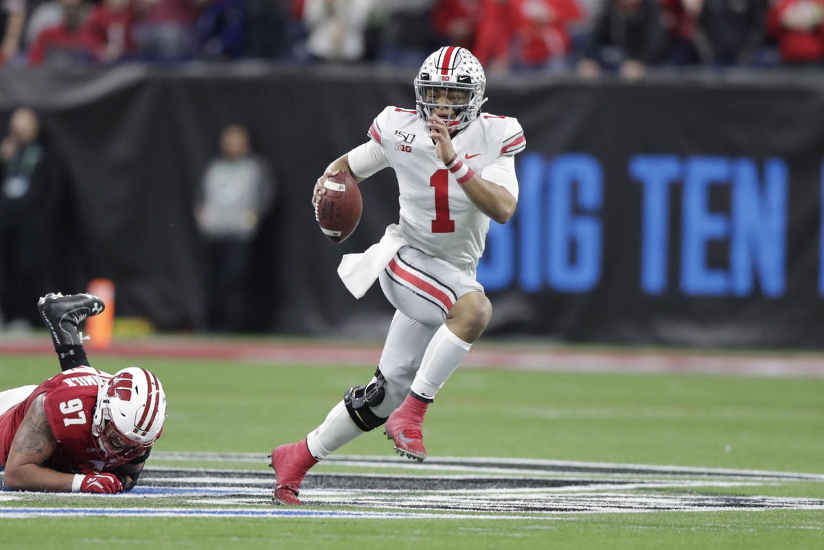 Ohio State quarterback Justin Fields (1) runs with the ball past Wisconsin defensive end Isaiah ...