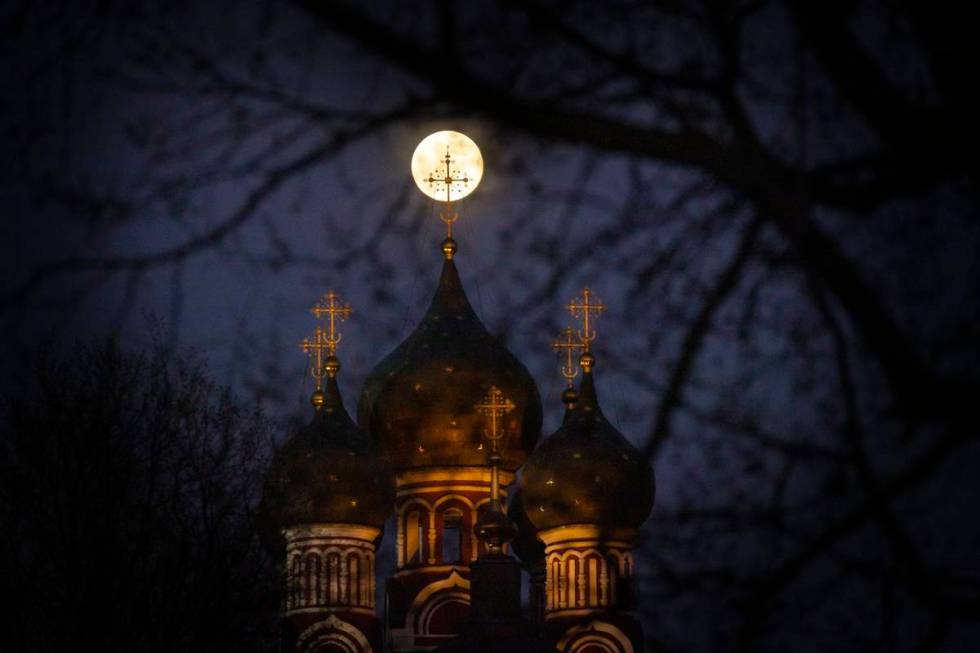 The supermoon rise behind an illuminated cross from a Christian Orthodox church in Moscow, Russ ...