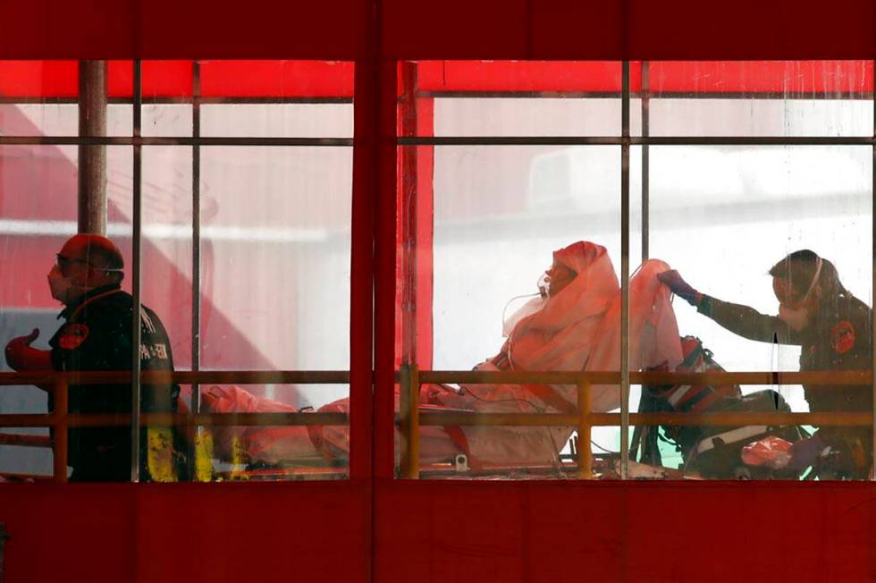 Emergency medical technicians wheel a patient into Elmhurst Hospital Center's emergency room, T ...