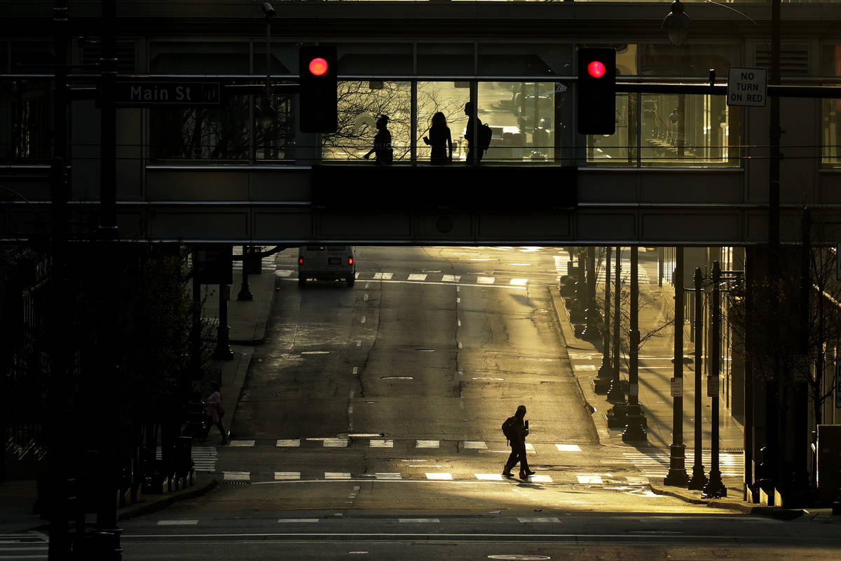 FILE - In this April 8, 2020, file photo pedestrians make their way through a deserted downtown ...