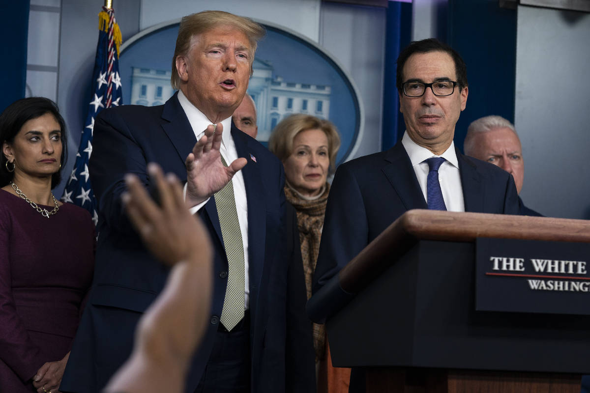 FILE- In this March 17, 2020 file photo Treasury Secretary Steven Mnuchin, right, listens as Pr ...