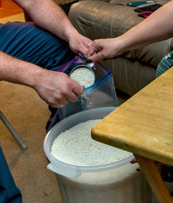 Marty Coon, left, holds a bag for his wife Veronica who scoops in rice for a food donation drop ...