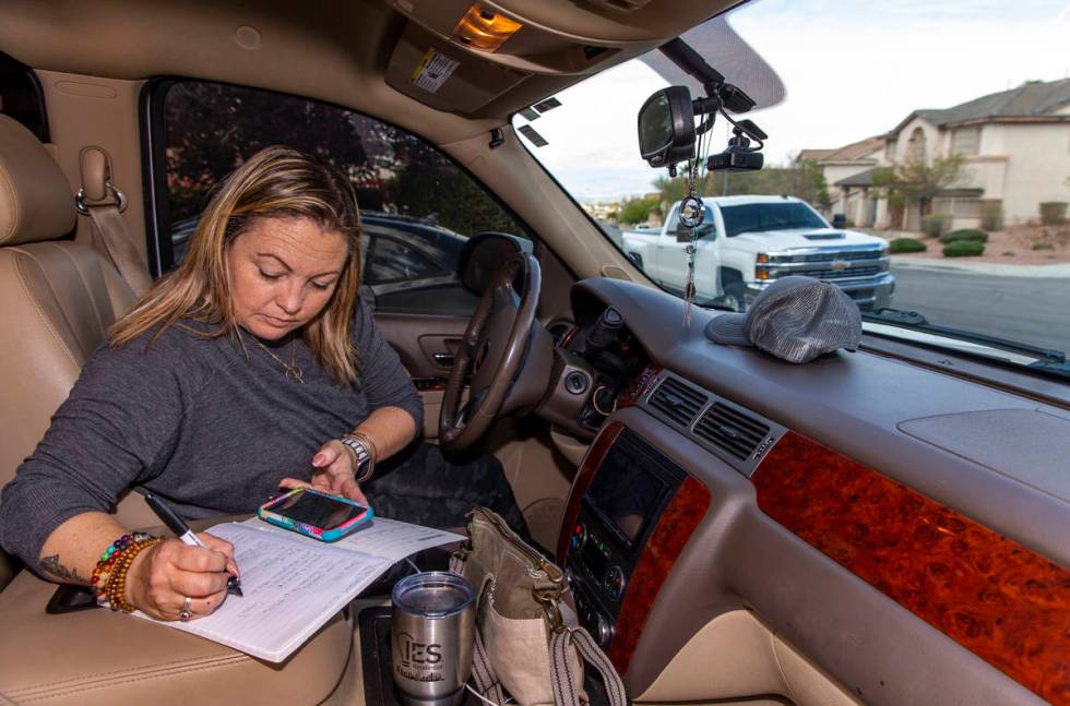 Kat Morris checks her list of deliveries of food and supplies for more donation drops with the ...