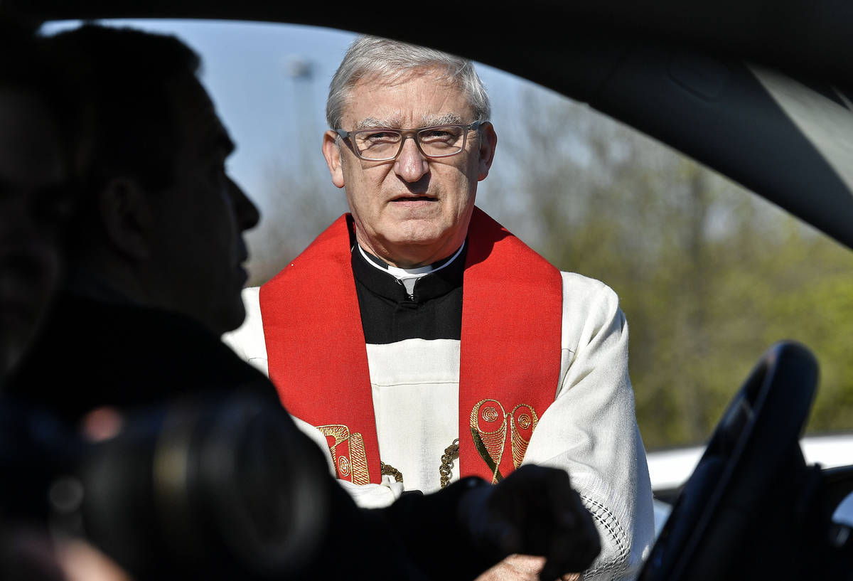 Priest Frank Heidkamp talks to believers in their cars prior a Good Friday church service at a ...