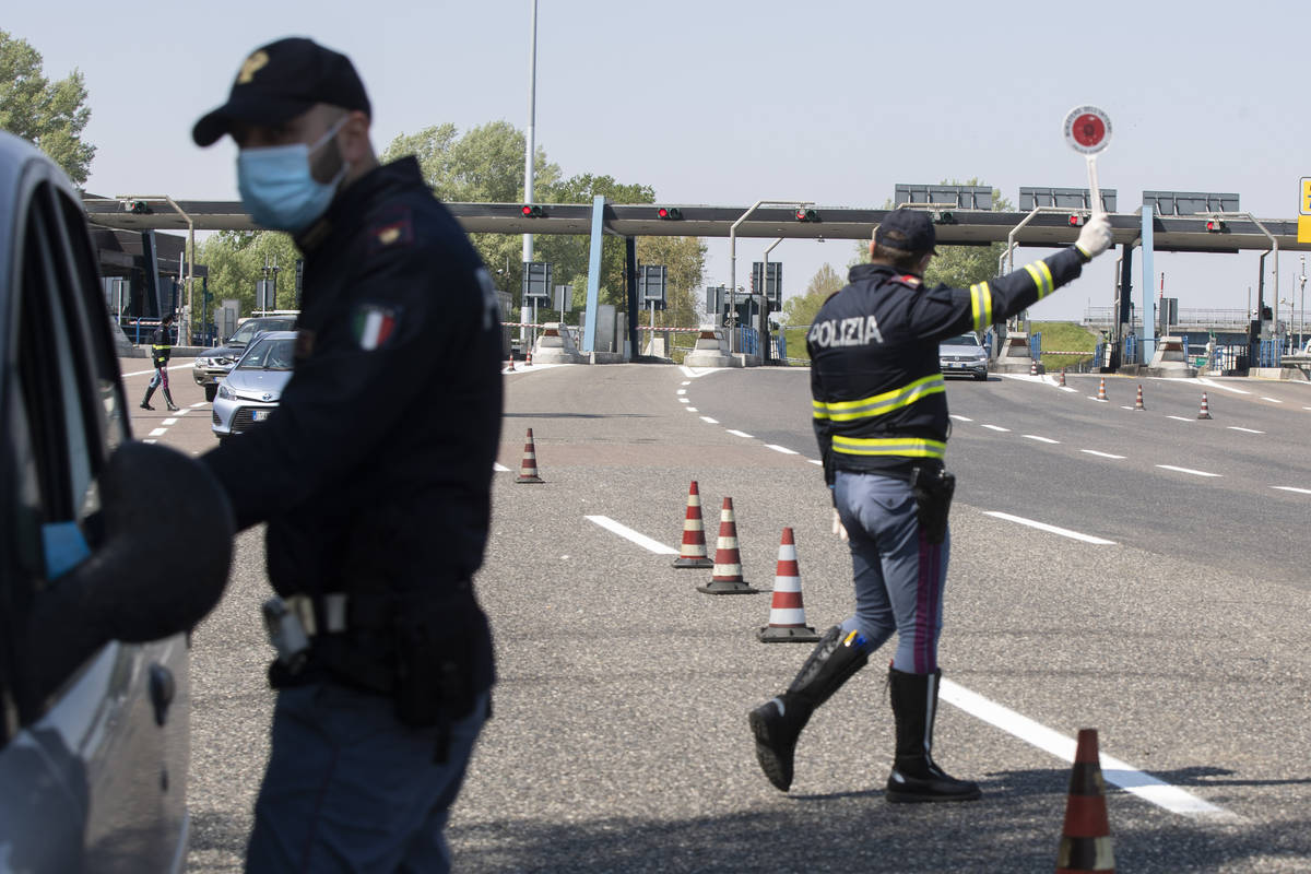 Police officers stop cars at the Melegnano highway barrier entrance, near Milan, Italy, Saturda ...