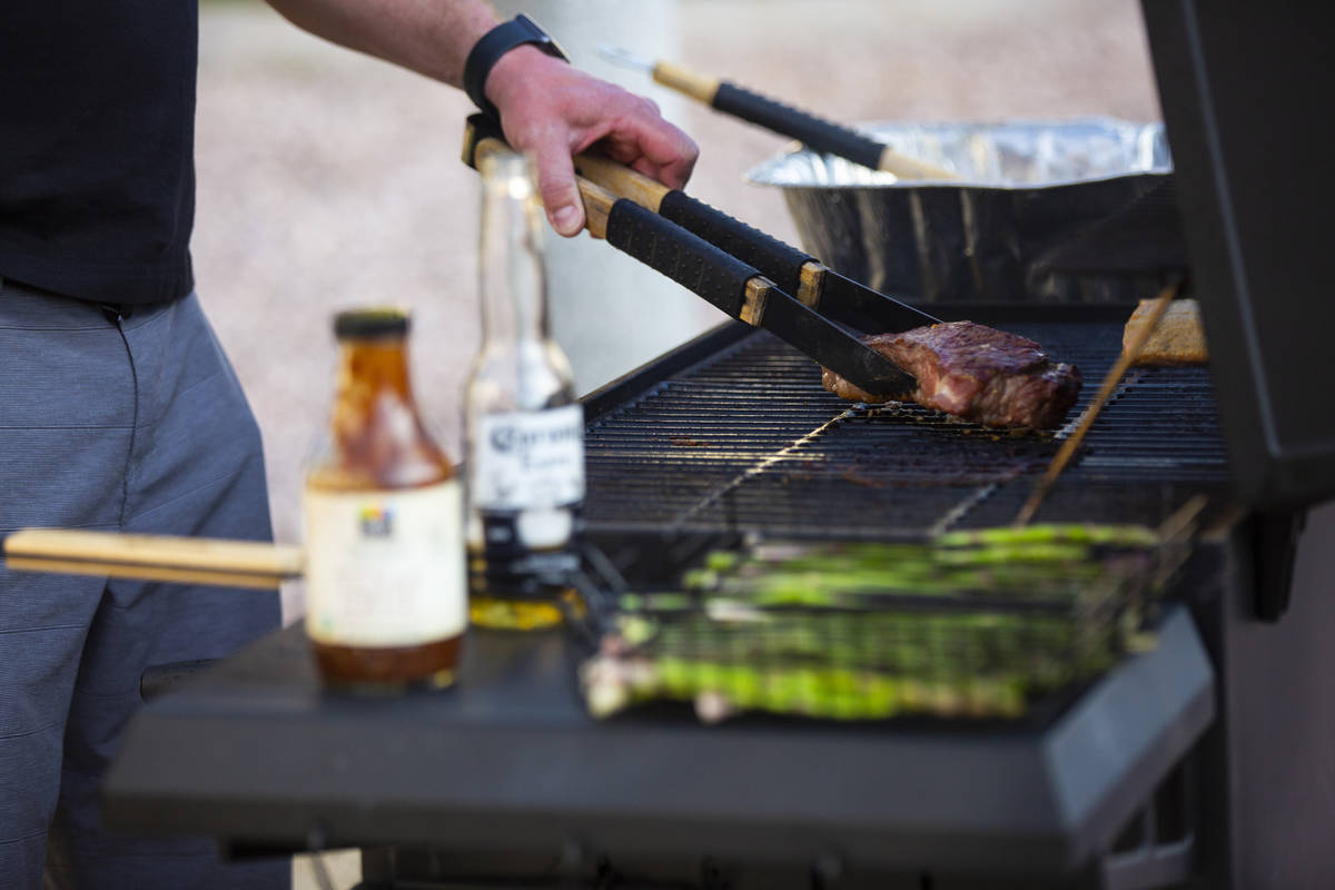 Noah Cross grills outside of his home while participating in a neighborhood front yard party an ...