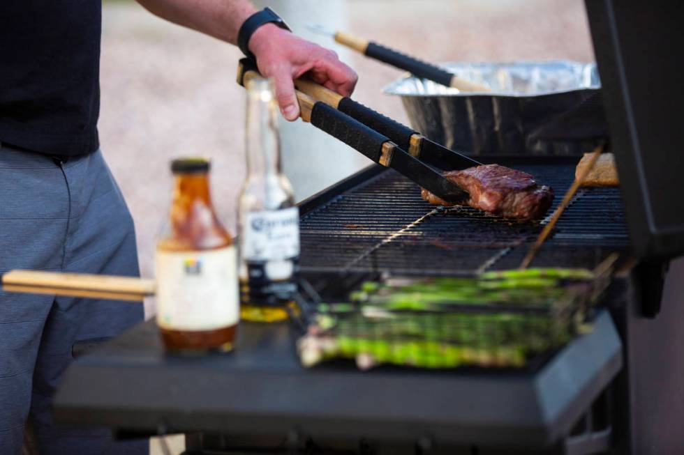 Noah Cross grills outside of his home while participating in a neighborhood front yard party an ...